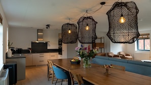 Een moderne keuken met een eethoek, met een houten tafel, stoelen en een blauwe bank.