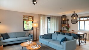 Una sala moderna con un sofá azul, una mesa de centro y un comedor con una mesa y sillas de madera.