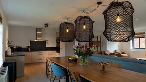 Una cocina moderna con zona de comedor, que incluye una mesa de madera, sillas y un sofá azul.