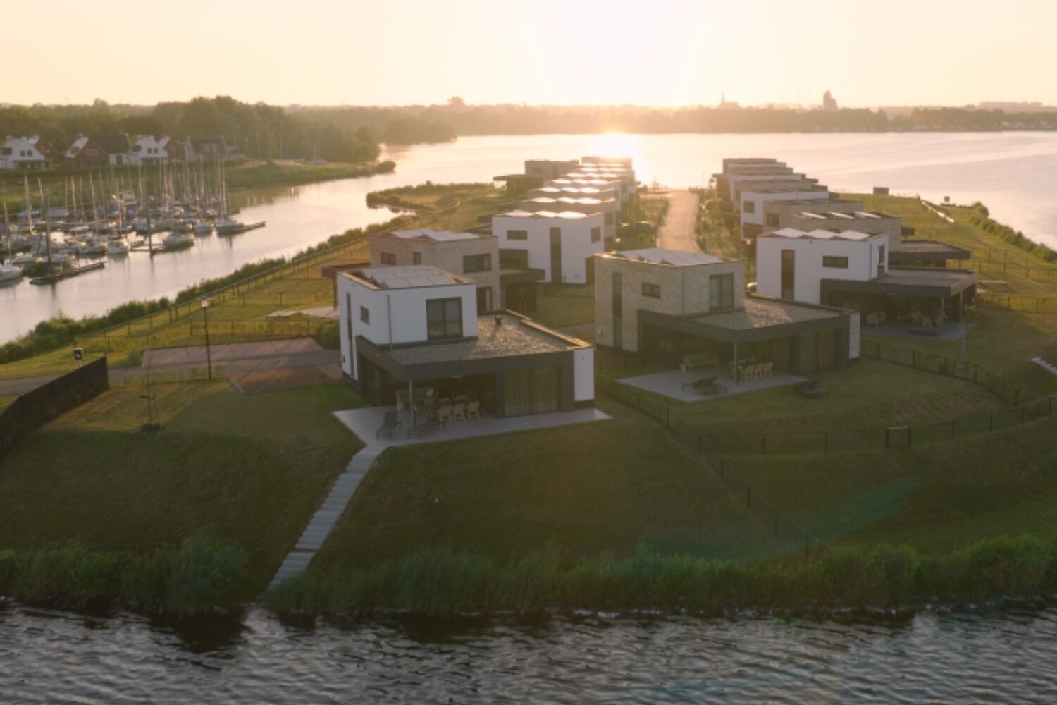 A modern residential area with detached houses, a marina with boats, and a river.