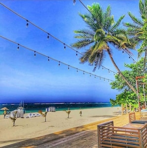 A beach scene with palm trees, string lights, and beach chairs. - El más Completo y Seguro. Free Wifi Fuera de Casa! (Puerto Plata)