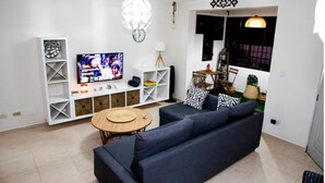 Un salon comprenant un canapé, un téléviseur, des étagères et une table à manger.