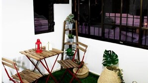 Ein Zimmer mit einem kleinen Holztisch und Stühlen, einer Hängeleuchte und einem Fenster mit schwarzen Rahmen.