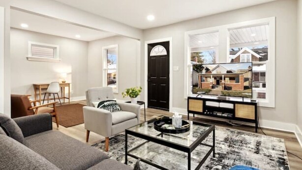 A modern living room with a sofa, armchair, coffee table, and a television.