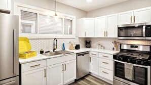 A modern kitchen with white cabinets, stainless steel appliances, and a yellow box on the counter.