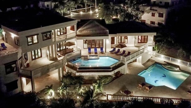 Un hôtel à plusieurs étages doté d’une piscine centrale, d’un espace extérieur aménagé et d’une façade bien éclairée.