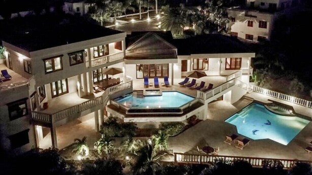 A multi-story hotel with a central swimming pool, outdoor seating, and a well-lit exterior.