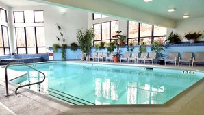 An indoor swimming pool with clear water, surrounded by windows and potted plants. - SlopeSide- Pool, Grill, Hot tub, Views! (Killington)