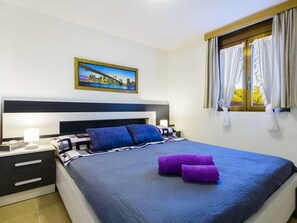Relax in a spacious room with a large bed, two bedside tables, and a framed cityscape above.