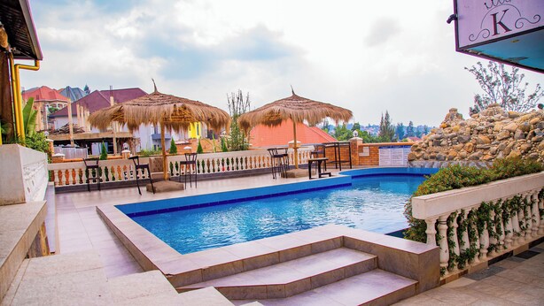 A swimming pool with steps leading into it, surrounded by a fence and umbrellas. - The Keza Hotel and Apartments (Kigali)