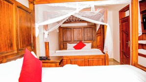 A wooden four-poster canopy bed with a red pillow, wooden headboard, and a nightstand with a telephone. - The Keza Hotel and Apartments (Kigali)