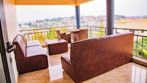 A balcony with a sofa, a small table, and a chair. - The Keza Hotel and Apartments (Kigali)