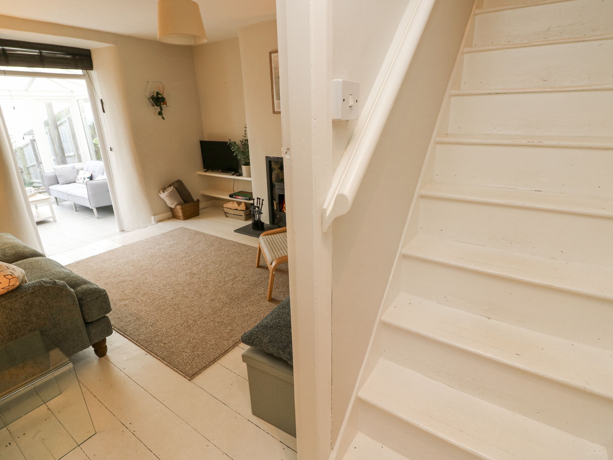 A living room with a sofa, a fireplace, a television, and a staircase.
