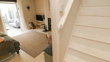A living room with a sofa, a fireplace, a television, and a staircase.