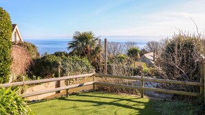 A wooden fence with a grassy area in the foreground and a view of the sea in the background. - Saltwater Cottage (Ventnor)