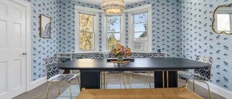 A dining area with a black table, wooden bench, and patterned chairs.