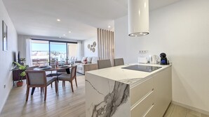 A modern kitchen with a marble countertop, a built-in oven, and a coffee machine.
