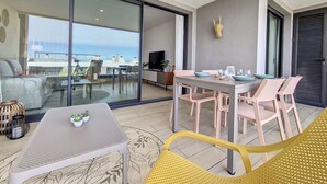 A modern living room with a balcony, a dining area, and a TV.