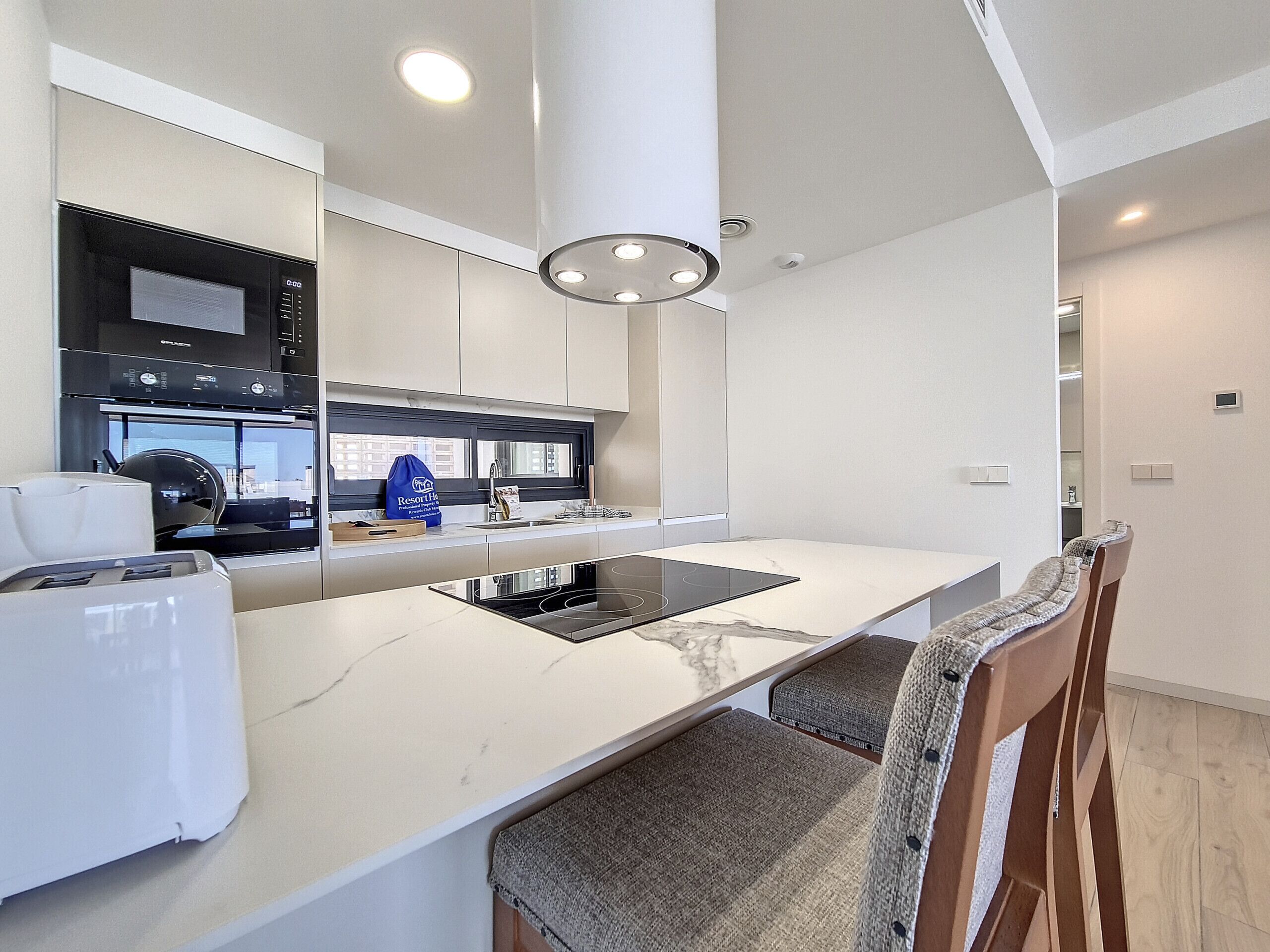 A modern kitchen with a large island, built-in appliances, and a view to the outside.