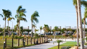 Un camino que lleva a un área de piscina rodeada de palmeras y edificios modernos.