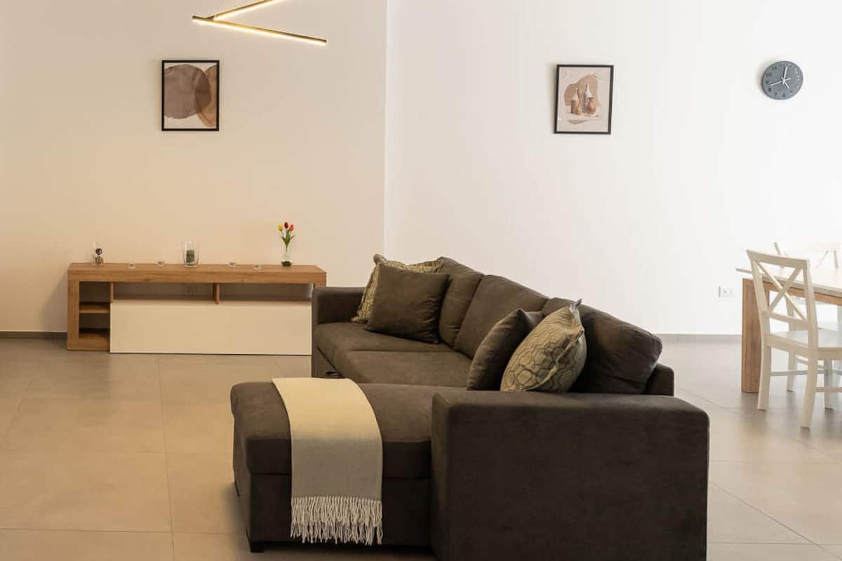 A modern living room with a sectional sofa, a wooden console table, and a minimalist pendant light.