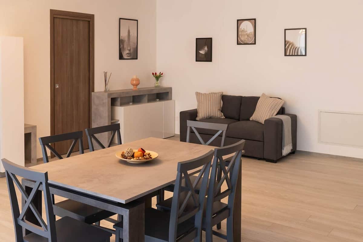 A modern living room with a dining area, featuring a sofa, a coffee table, and a dining table with chairs.