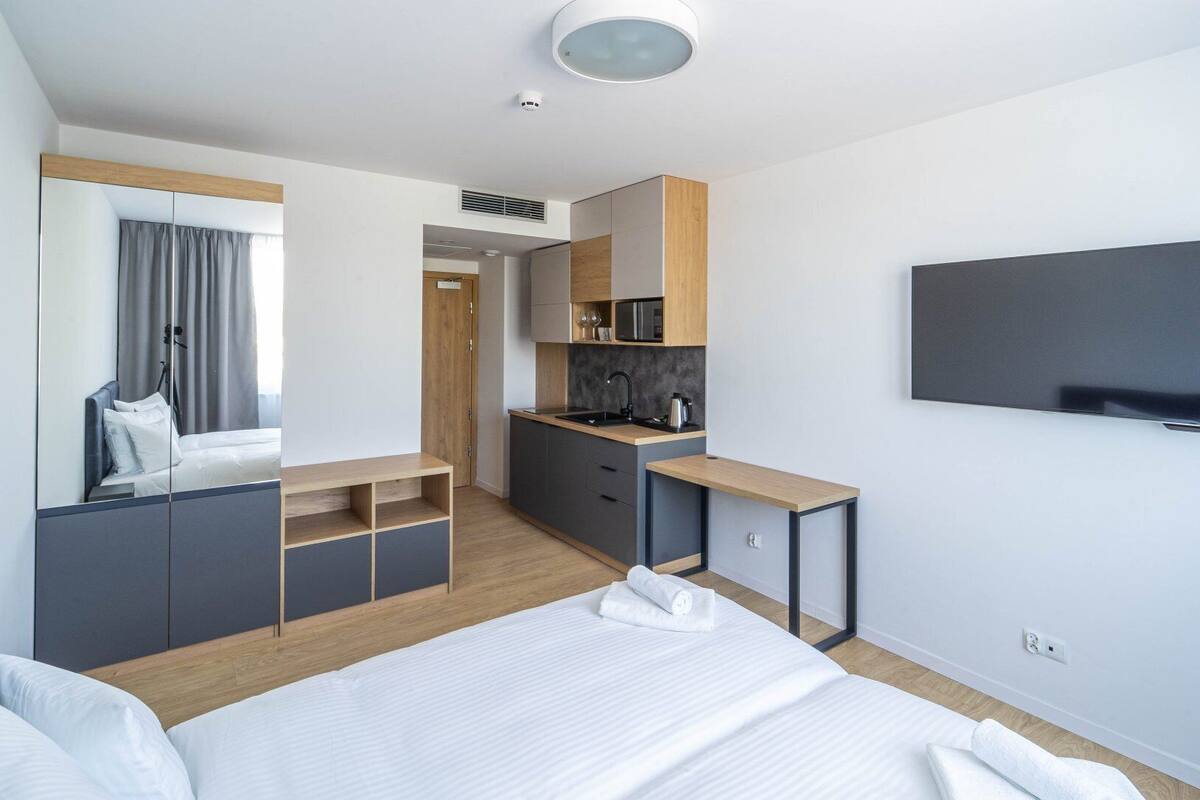 Et moderne hotelværelse med seng, skrivebord, tekøkken og fjernsyn.