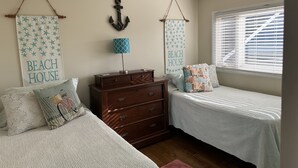 Un dormitorio con dos camas, un aparador y dos adornos en la pared.
