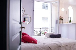 Enjoy a peaceful retreat with a large window offering a view of the outside, a comfortable bed, and a stylish table with a vase and flowers.