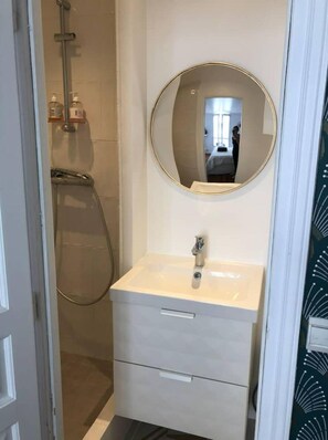 Bathroom features a pedestal sink, shower area with tub and handheld showerhead.