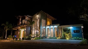 Una casa moderna con una entrada bien iluminada, ventanas amplias y un camino de acceso pavimentado.