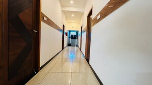 A hallway with wooden doors and white walls, leading to a brightly lit room. - Raja residency near ISHA ADIYOGI ALANDURAI Siruvani Coimbatore ,Tamilnadu, India (Alanthurai)