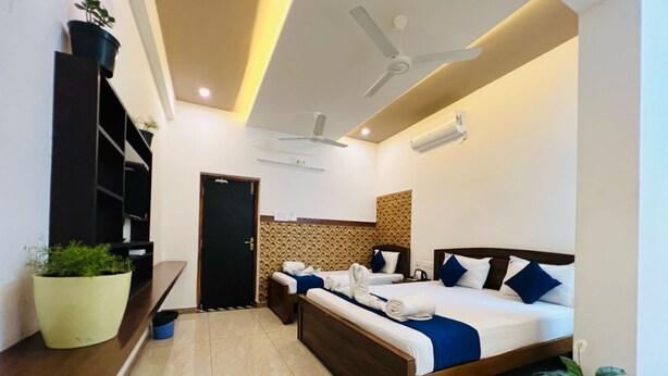 A modern hotel room with two beds, a ceiling fan, and a large potted plant. - Raja residency near ISHA ADIYOGI ALANDURAI Siruvani Coimbatore ,Tamilnadu, India (Alanthurai)