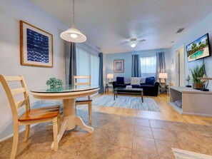 A living room with a dining table, chairs, a sofa, a TV, and a ceiling fan. - Siesta Key Sanctuary -Pool-Kayaks-TikiHut-King bed (Siesta Key)