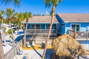 A two-story building with a balcony, palm trees, and a thatched umbrella. - Solitude Suite Studio-Siesta Key-Waterfront Resort (Siesta Key)