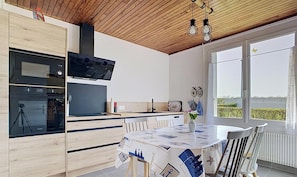 A modern kitchen with wooden cabinets, a built-in oven, and a dining area with a table set for two.