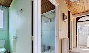 A bathroom with a toilet, a shower enclosure, and a radiator.