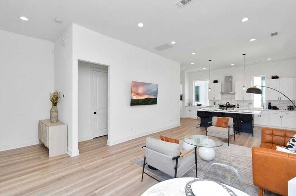 Una sala de estar moderna con comedor, cocina y un ventanal grande.