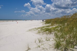 En strand med sand, klitter og sparsom vegetation.