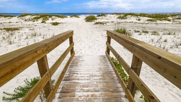 A wooden boardwalk leading to a sandy beach with dunes and a clear sky. - Ocean and Racquet 8208 (St. Augustine)