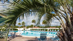 A pool area with lounge chairs and palm trees. - Ocean and Racquet 8208 (St. Augustine)