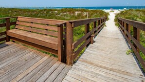 A wooden boardwalk leading to a beach with a bench on the left. - Ocean and Racquet 8208 (St. Augustine)