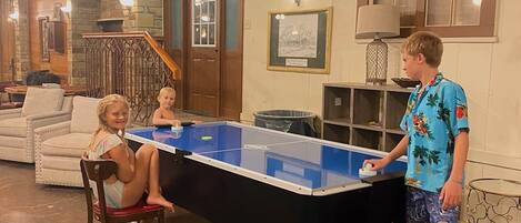 Una habitación con mesa de ping pong, sofá y escalera.