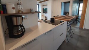 Moderni keittiö, jossa on sisäänrakennettu liesi, kahvinkeitin ja riippuvalaisin.