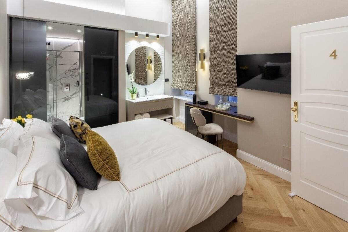 A modern bedroom with a large bed, a vanity with a mirror, and a door marked with the number 4.