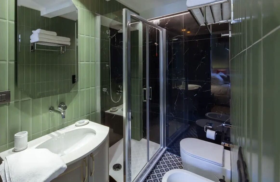 A bathroom with a glass-enclosed shower, a white sink, and a toilet.