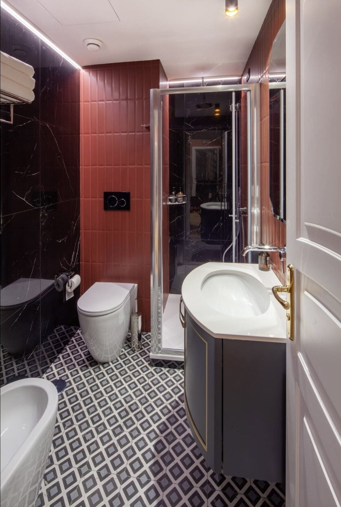 A modern bathroom with a marble floor, a toilet, a sink, and a shower area.