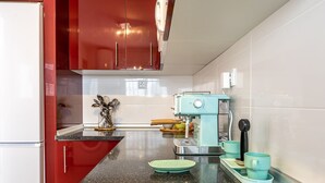 A kitchen with red cabinets, a coffee machine, and teal cups on the counter. - Your Beach Front Retro Hideaway in Salou (Salou)