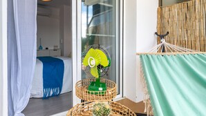A room with a bed, a green fan, a wicker basket, and a green curtain. - Your Beach Front Retro Hideaway in Salou (Salou)