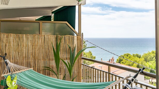 A balcony with a hammock, a fan, and a view of the ocean. - Your Beach Front Retro Hideaway in Salou (Salou)